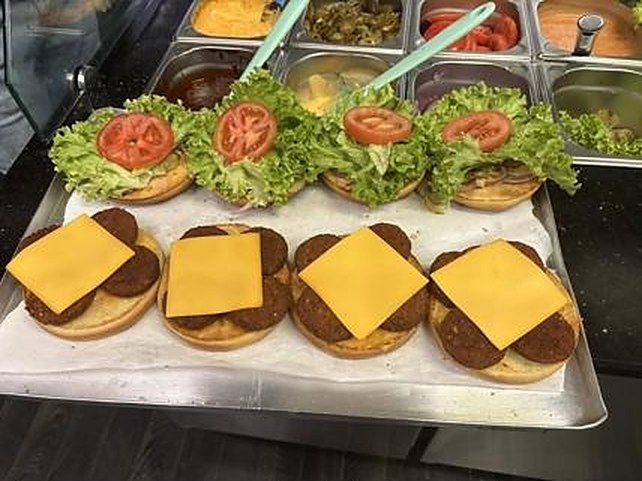 Frisch belegte Cheeseburger mit Chesterkäse auf dem Blech bei REDA's Imbiss